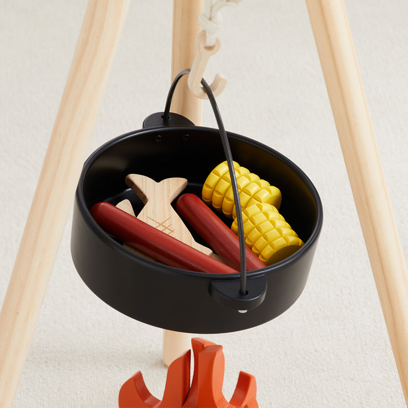 Black mini grill with toy hot dogs, corn, and wooden skewers on a white background