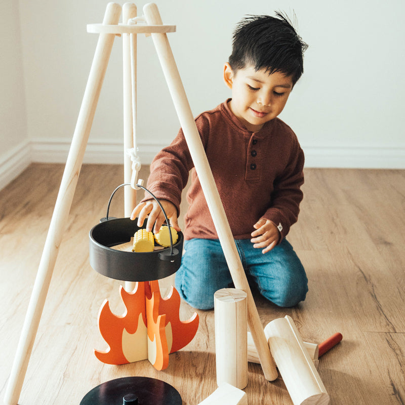 Child playing with a toy campfire set on a wooden floor