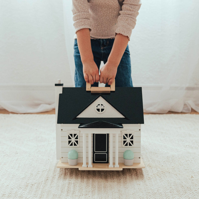Person holding a small model house on a carpeted floor