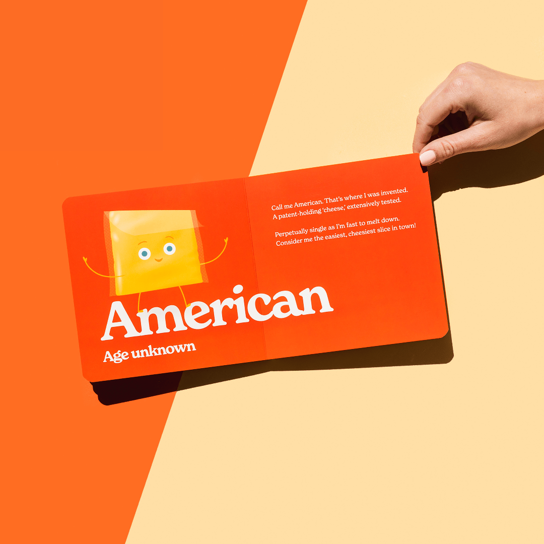Card with a cartoon character and text held by a hand against an orange and beige background