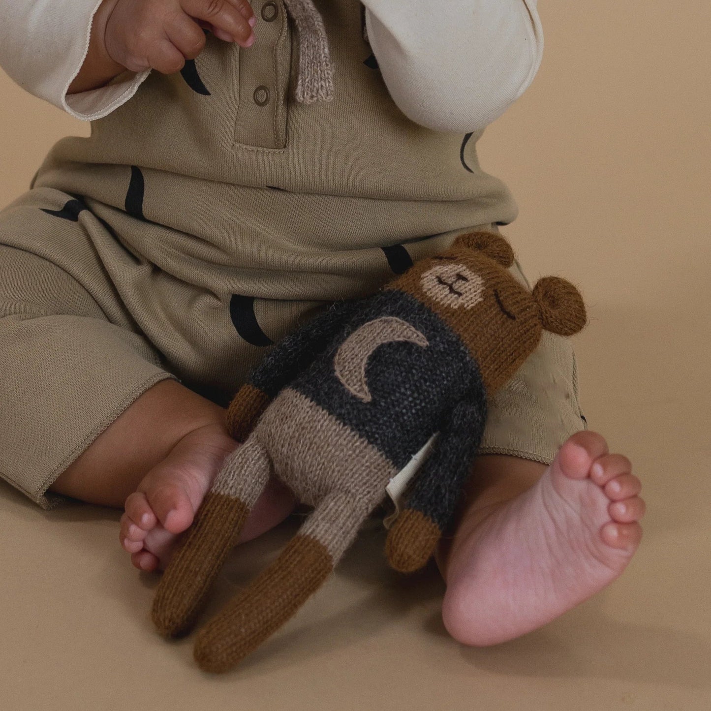 Child holding a plush bear toy on a beige background