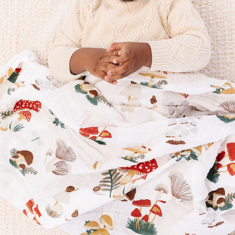 Child wrapped in a colorful blanket with a white knit blanket underneath