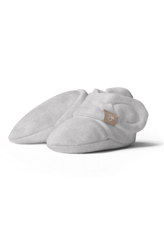 Light gray baby booties with a brand logo on a transparent background