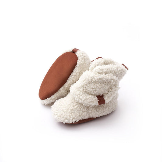 Pair of white fuzzy slippers with brown soles on a white background