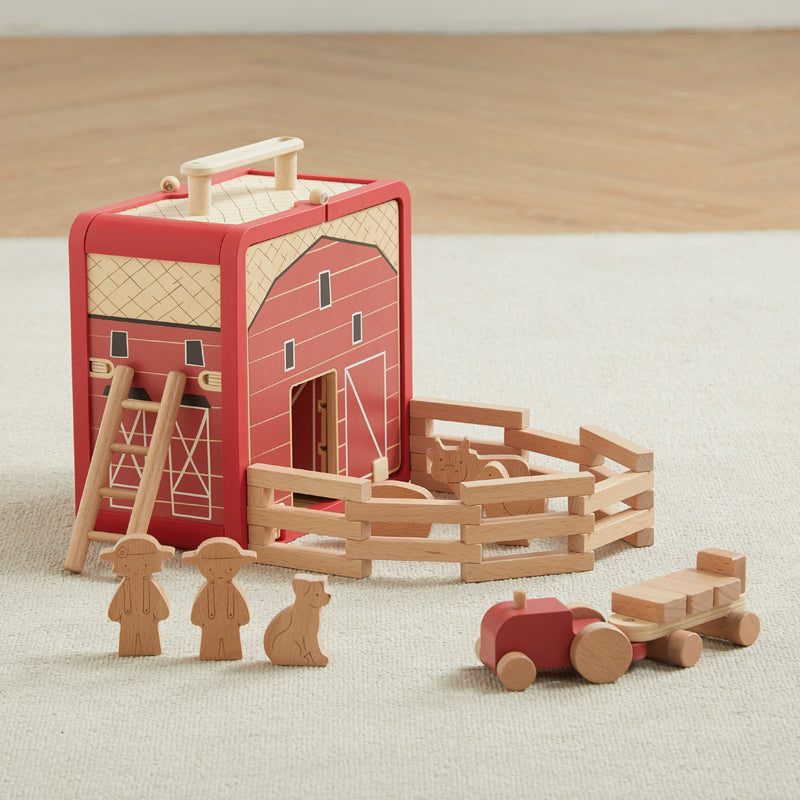 Wooden toy barn set with accessories on a neutral surface