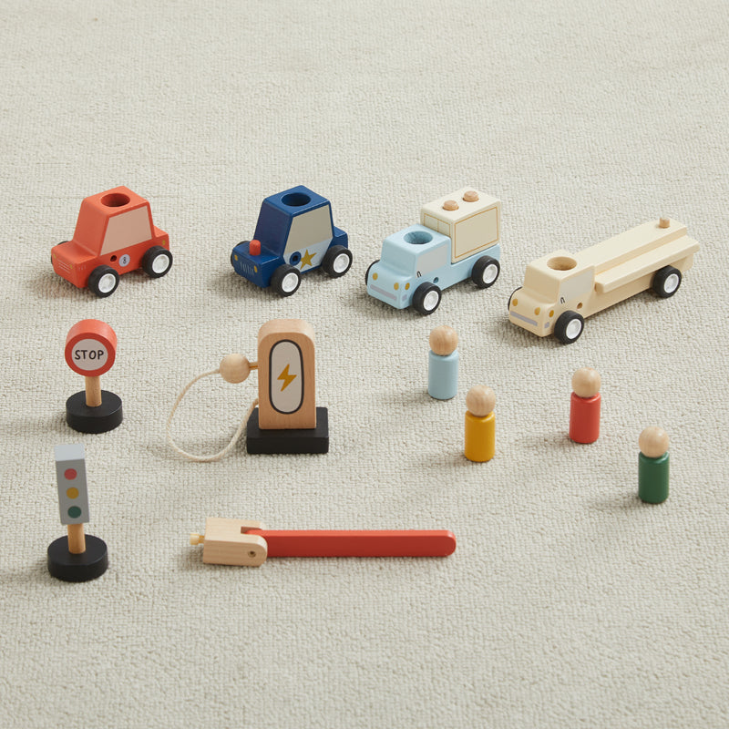 Set of colorful wooden toy vehicles and figures on a beige surface
