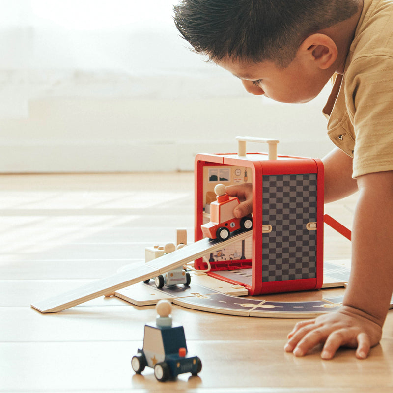 Child playing with a toy train set on a wooden floor.