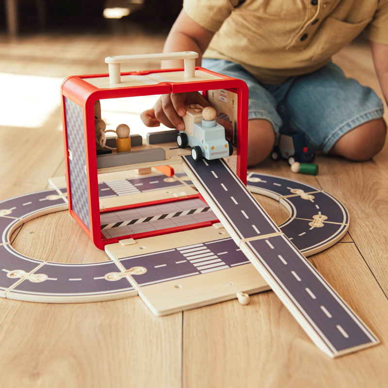 Child playing with a toy car on a wooden track set