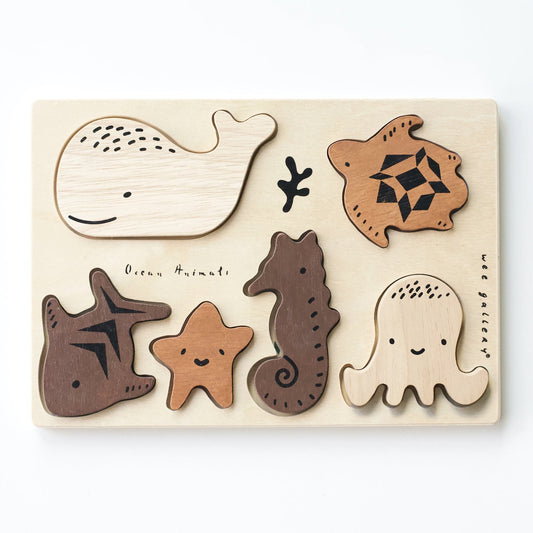 Wooden puzzle with ocean animal shapes on a light beige background