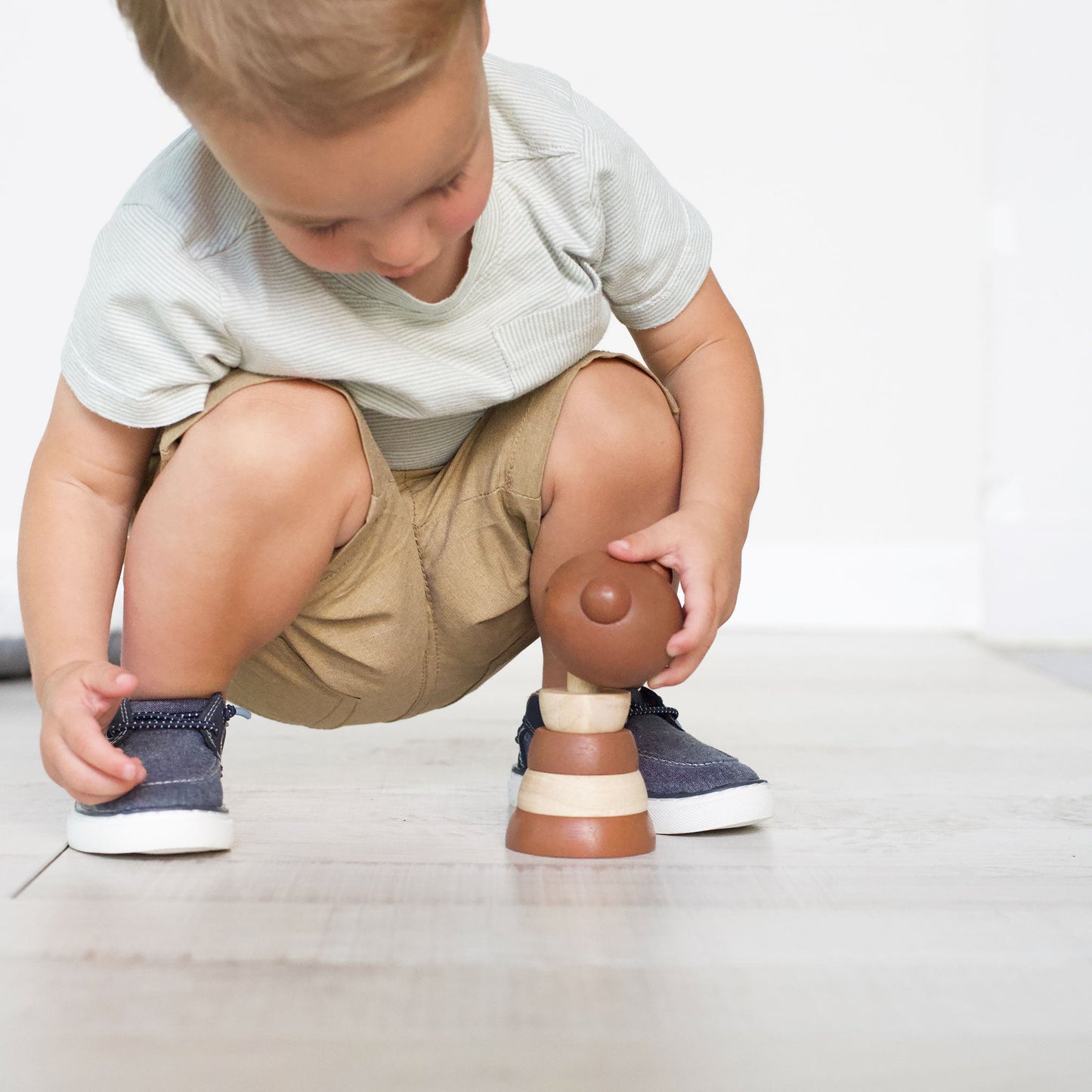 Child playing with a toy horse on a light-colored floor