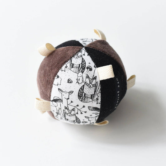 A sensory taggy ball with a woodlands theme, including animals and nature elements, with different textures and a rattle inside.