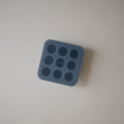Blue silicone mold with multiple round cavities on a light gray background