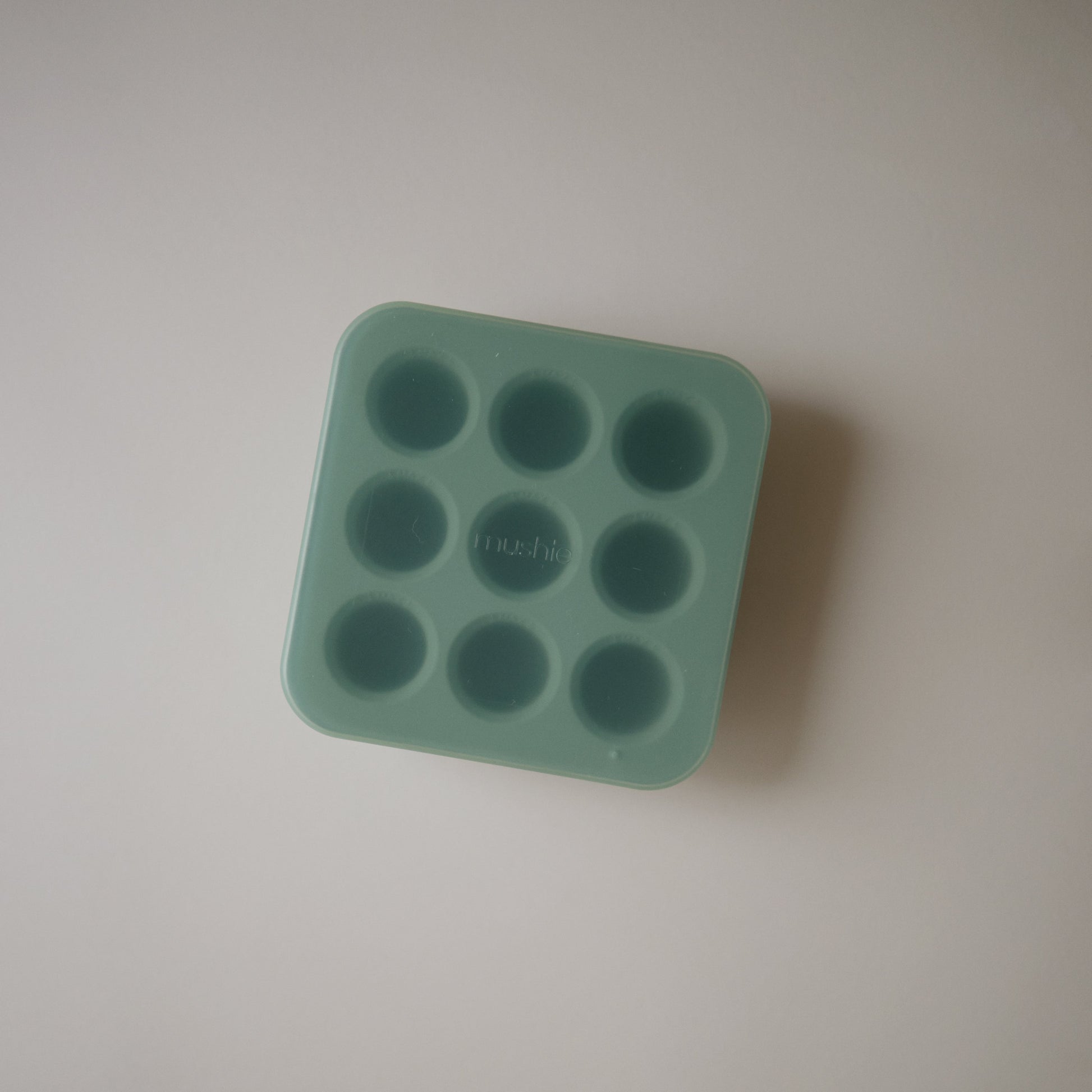 Green silicone mold with multiple small cavities on a light gray background