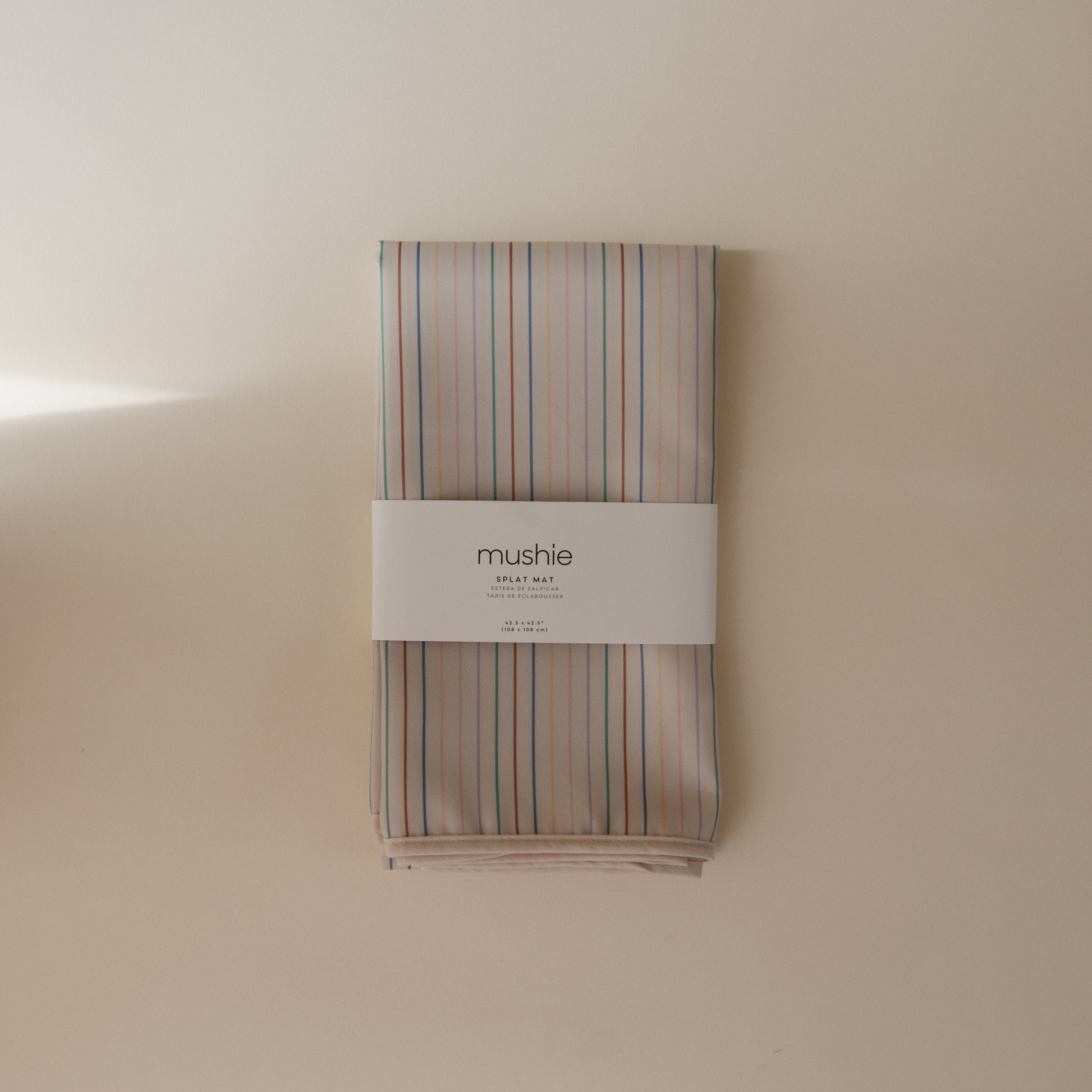 Striped fabric roll with 'mushie' label on a beige background