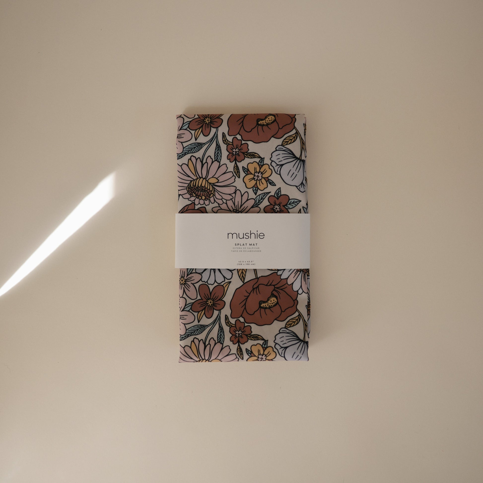 Floral-patterned product packaging with 'mushie' label on a beige background