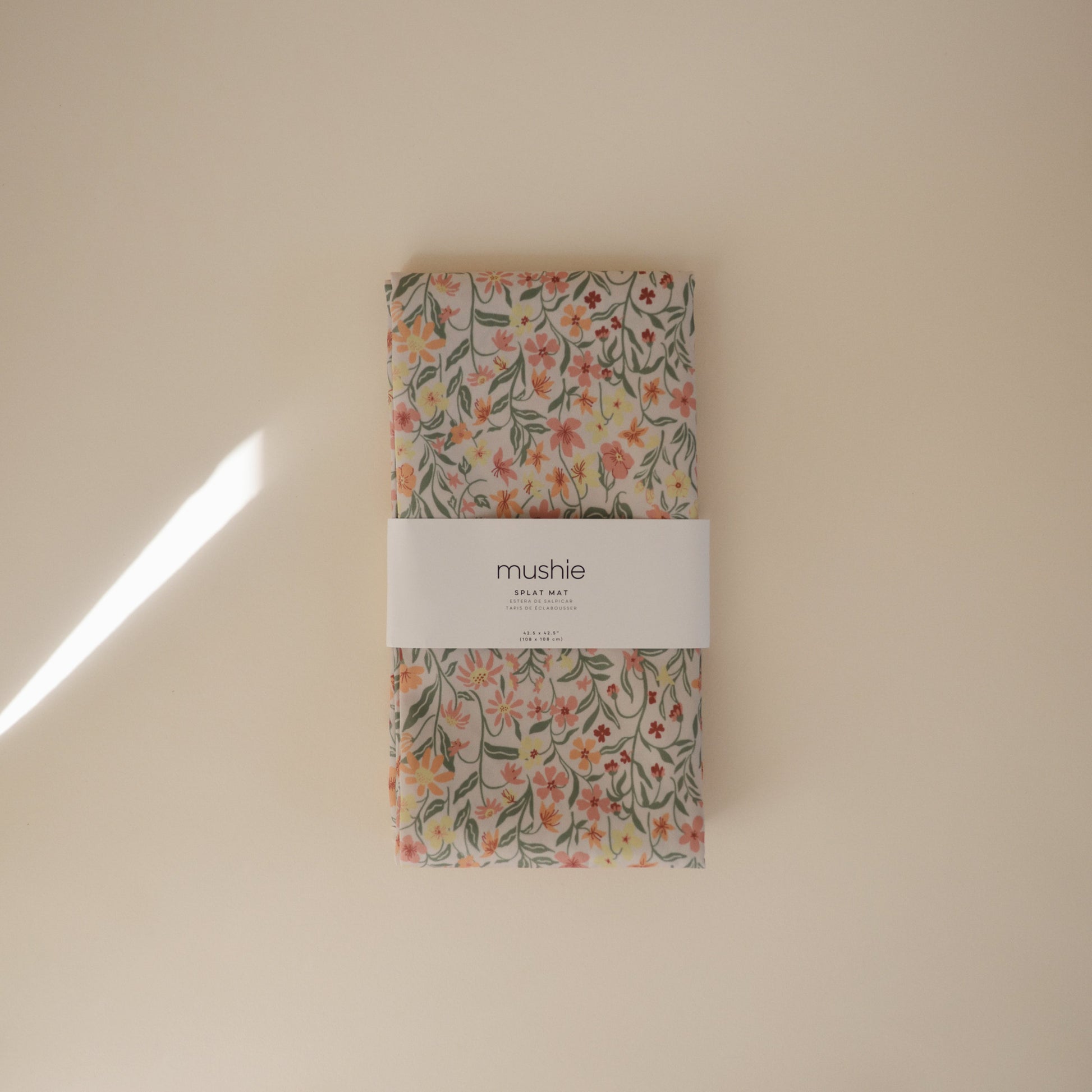 Floral-patterned product with 'mushie' label on a beige background