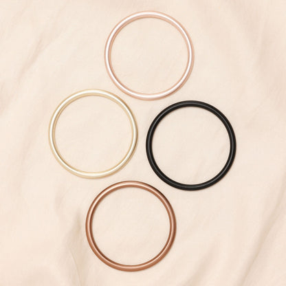 Set of five hair ties in gold, rose gold, silver, and black on a beige fabric background