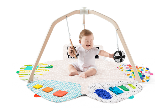 Baby playing with a colorful play gym on a white background