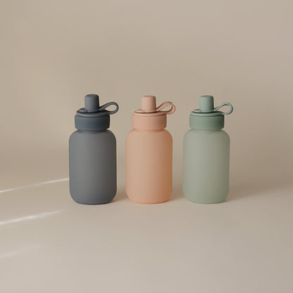Three colorful water bottles with different shades on a beige background