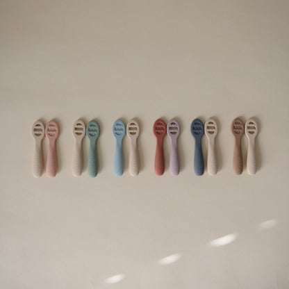 Row of baby teethers in various pastel colors on a light background