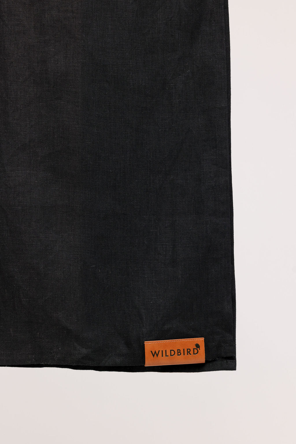 Black fabric with a leather patch featuring 'Wildbird' branding on a light background