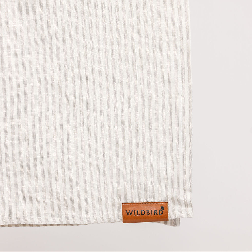 Textured white fabric with a leather tag labeled 'Wildbird' on a light gray background