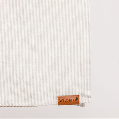 Textured white fabric with a leather tag labeled 'Wildbird' on a light gray background