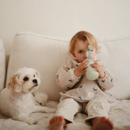 Child sitting on a couch with a dog, holding a green toy