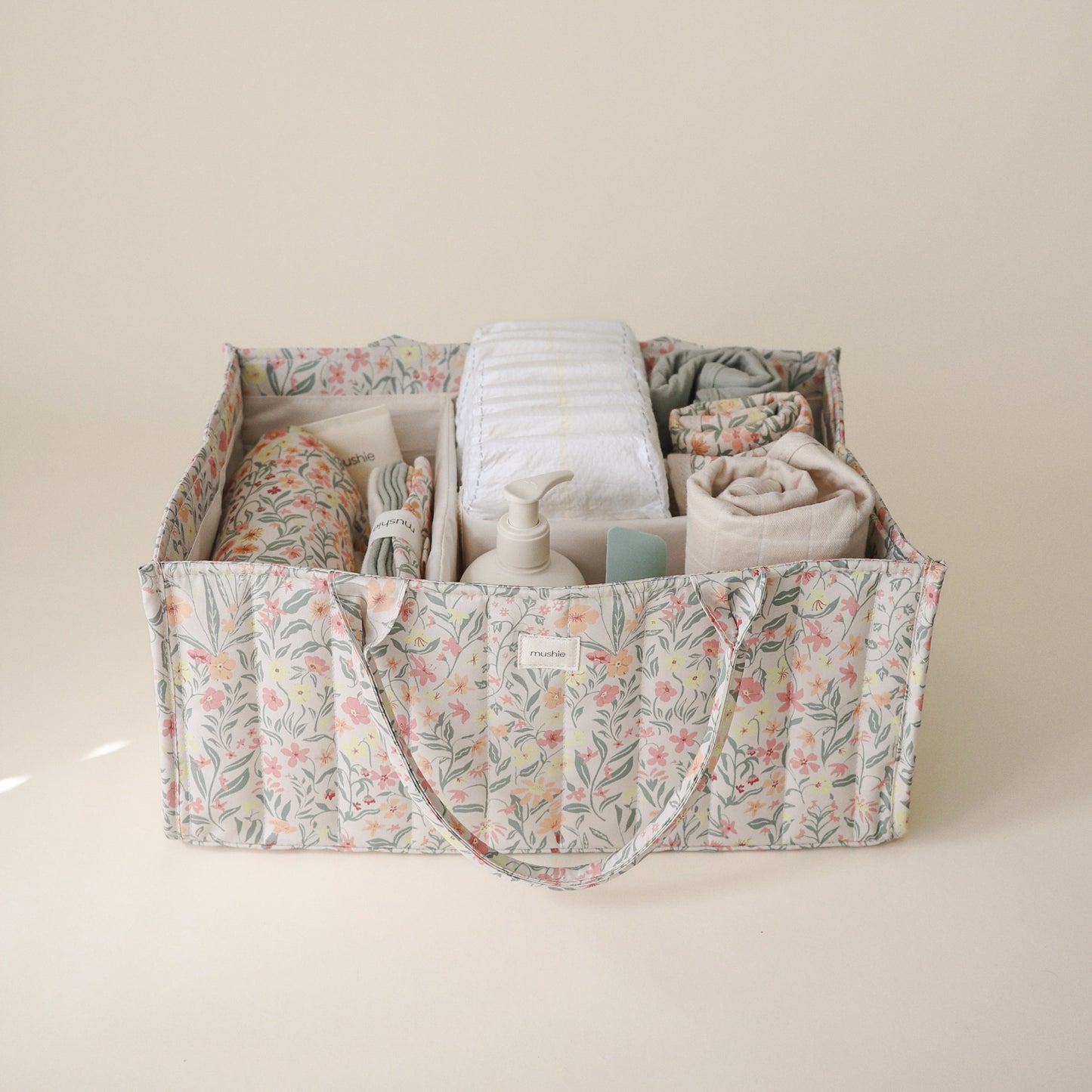 Floral-patterned storage bin filled with folded clothes on a beige background