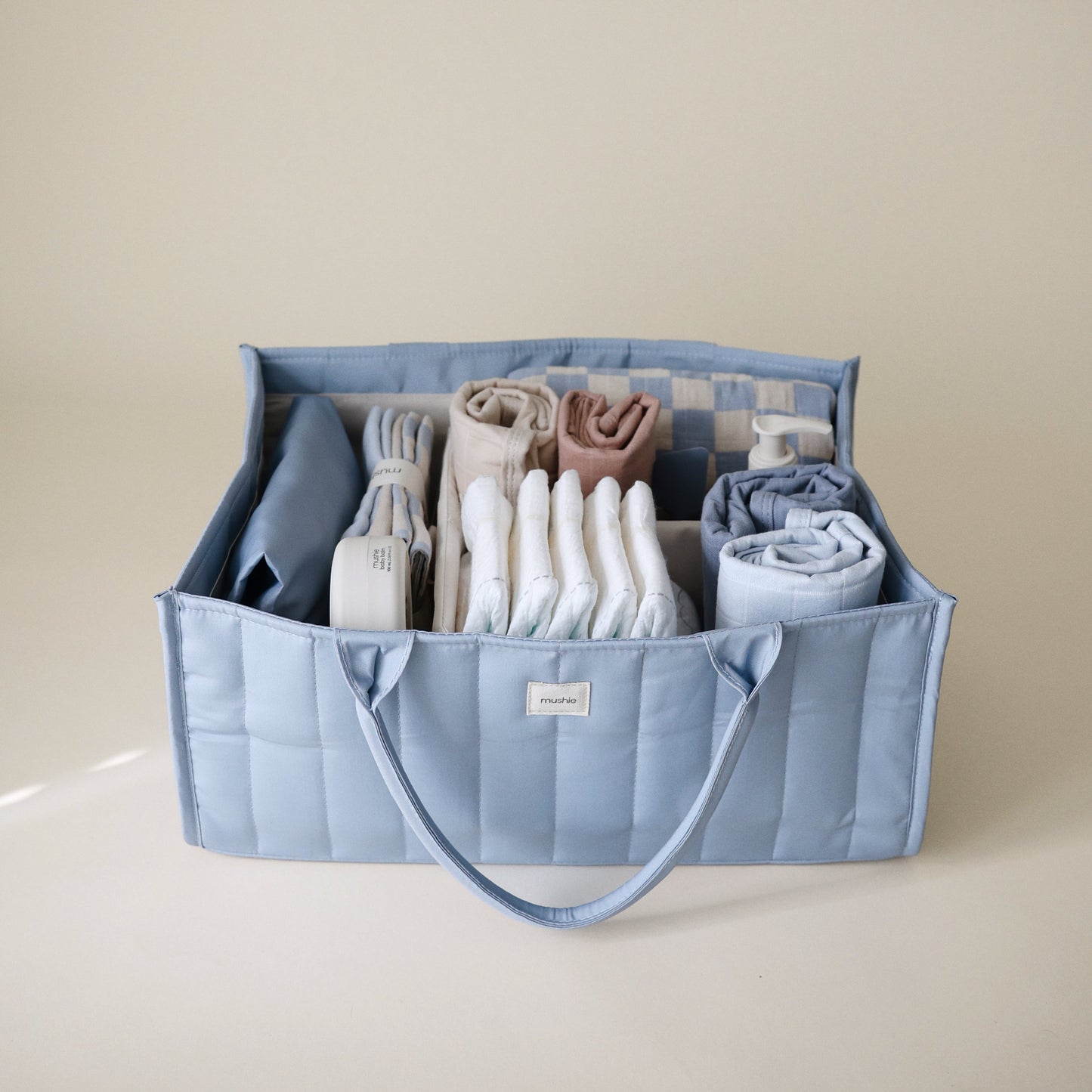 Blue storage caddy with folded clothes on a beige background