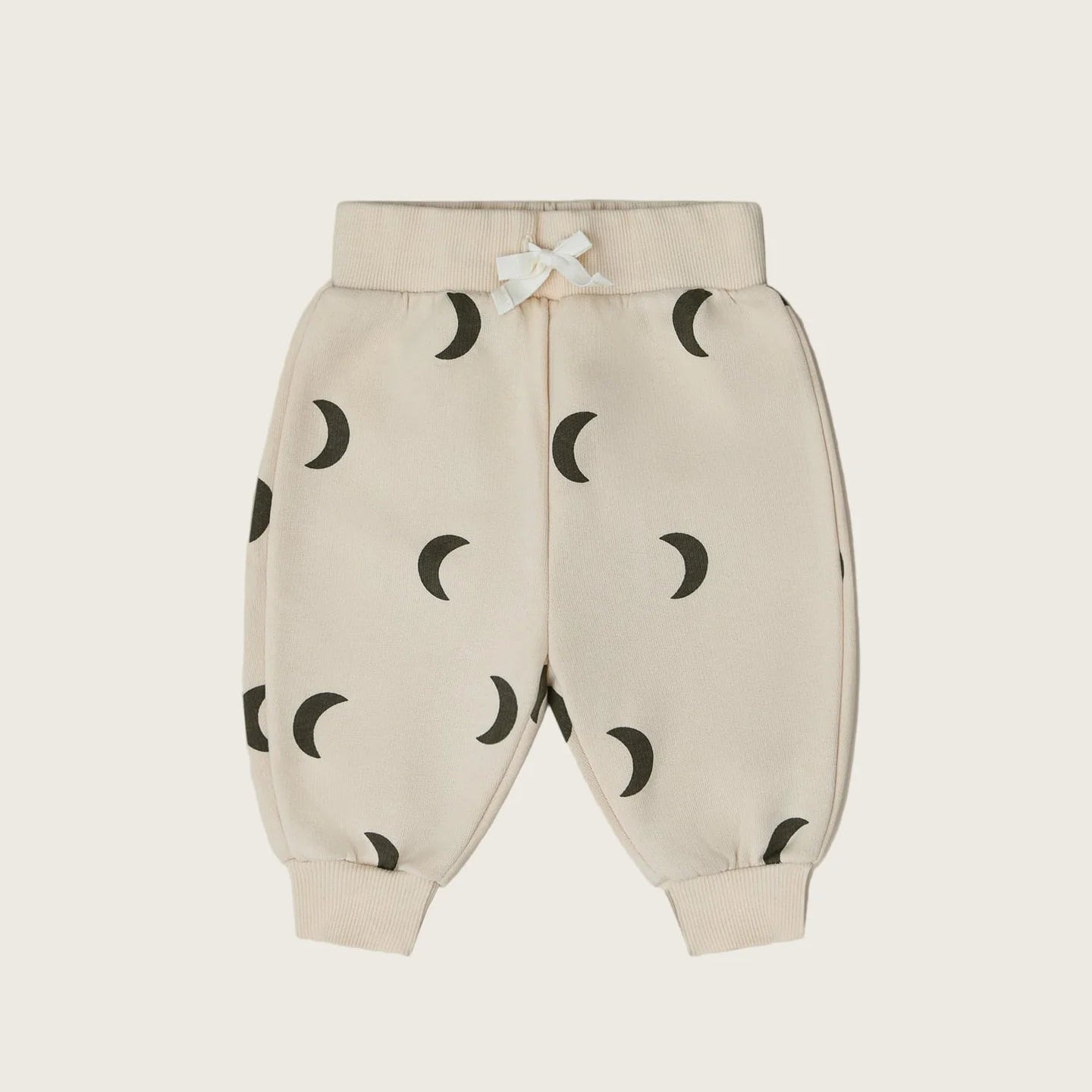 Beige baby pants with black moon pattern on a white background