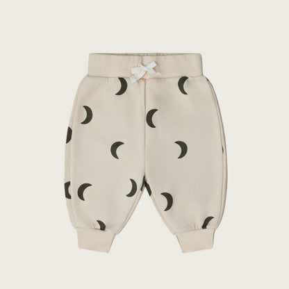 Beige baby pants with black moon pattern on a white background
