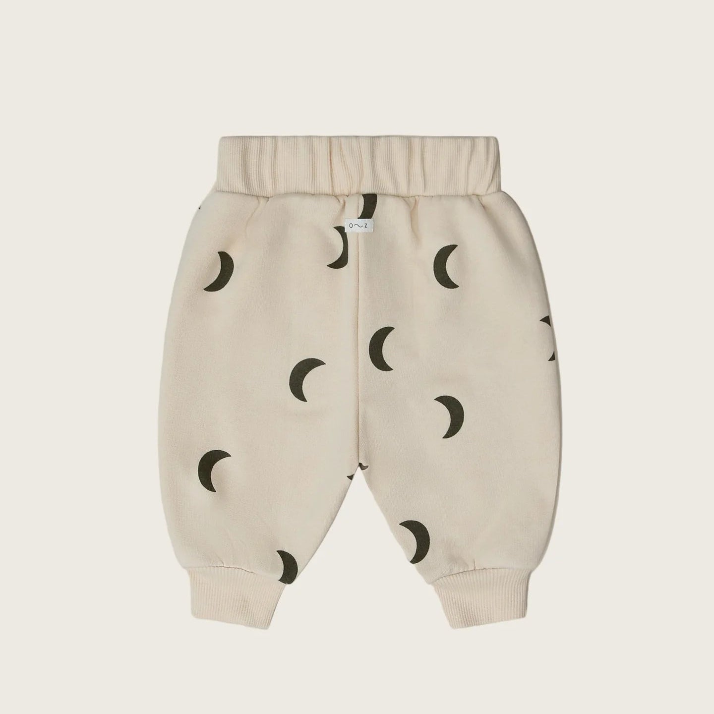 Beige baby pants with moon pattern on a light beige background