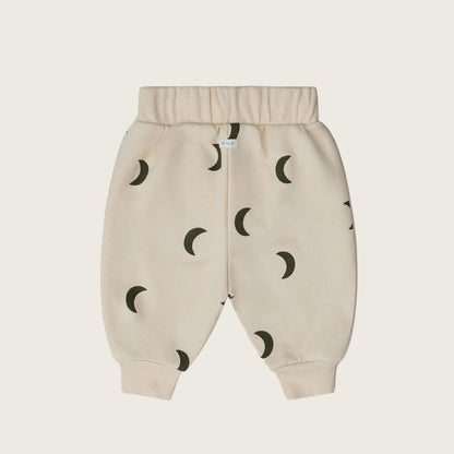 Beige baby pants with moon pattern on a light beige background