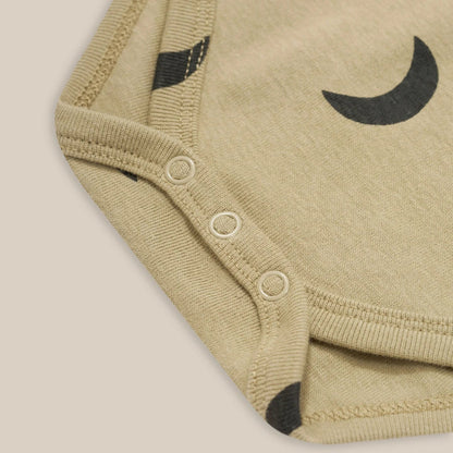 Close-up of a beige baby romper with black crescent moon design on a beige background