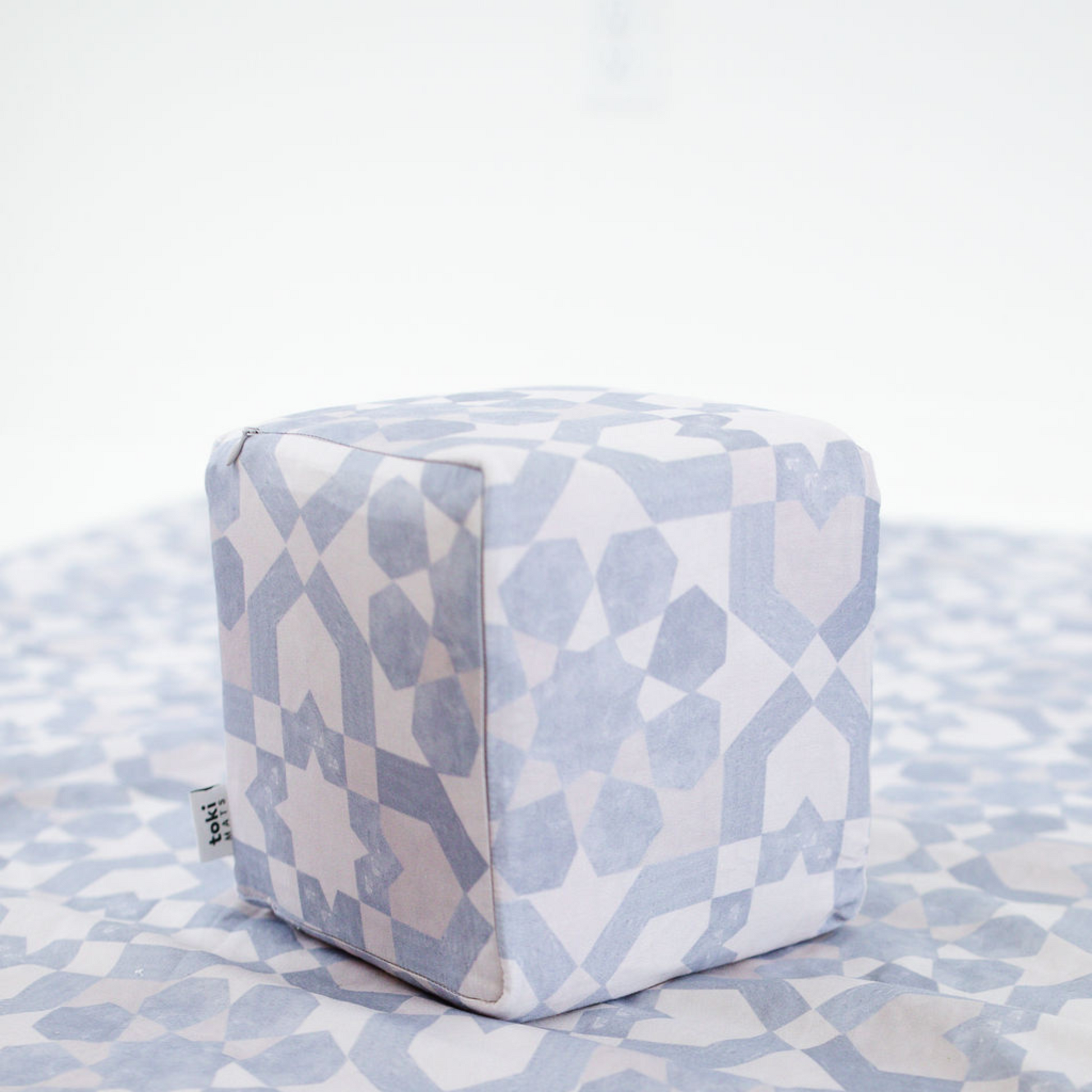 Cube-shaped ottoman with geometric pattern on a matching fabric surface