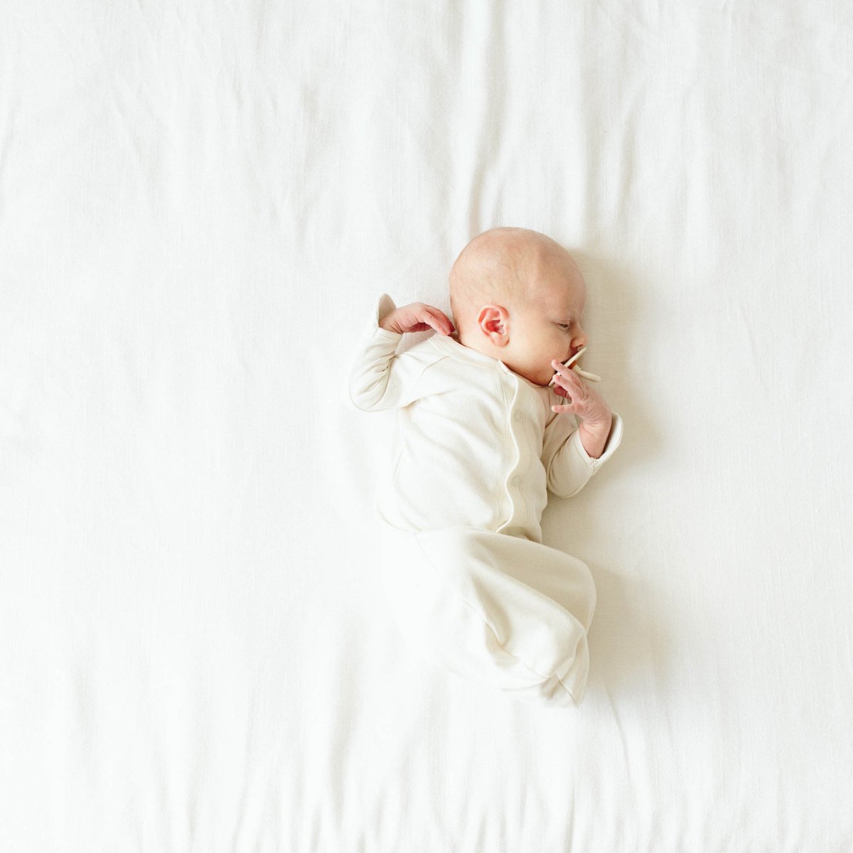 Newborn baby swaddled in a white blanket on a white background
