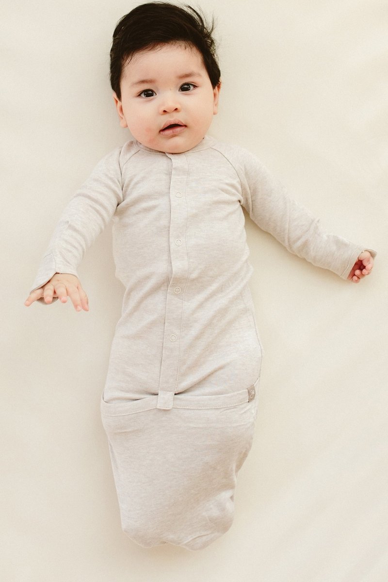 Baby in a light gray onesie on a plain background