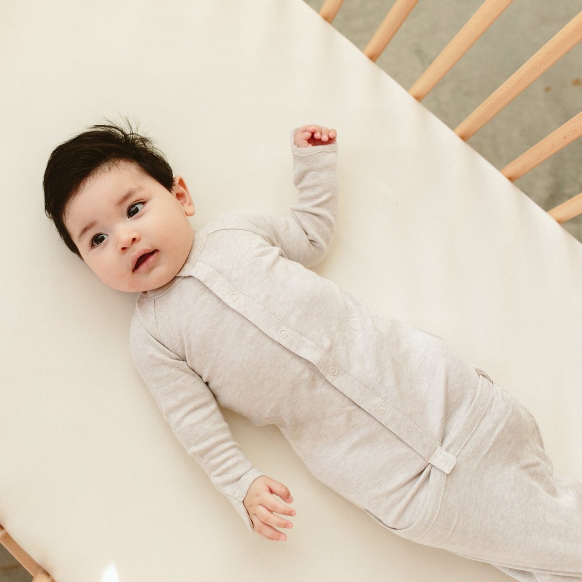 Baby lying on a white mattress in a crib