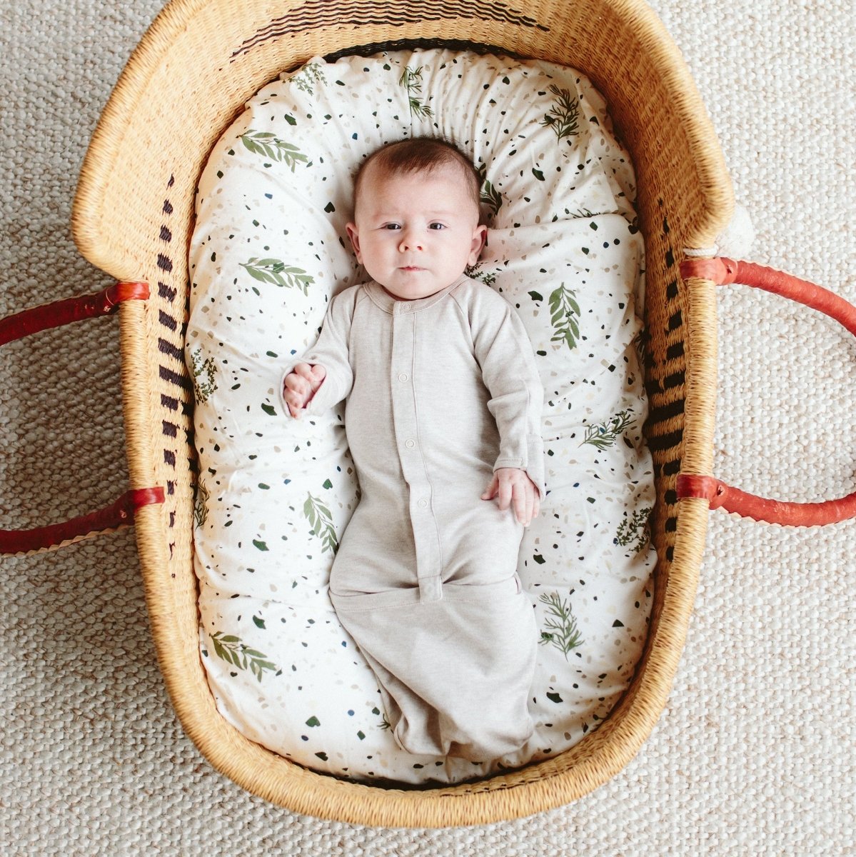 Baby in a woven crib with a patterned mattress
