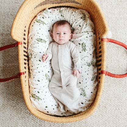 Baby in a woven crib with a patterned mattress