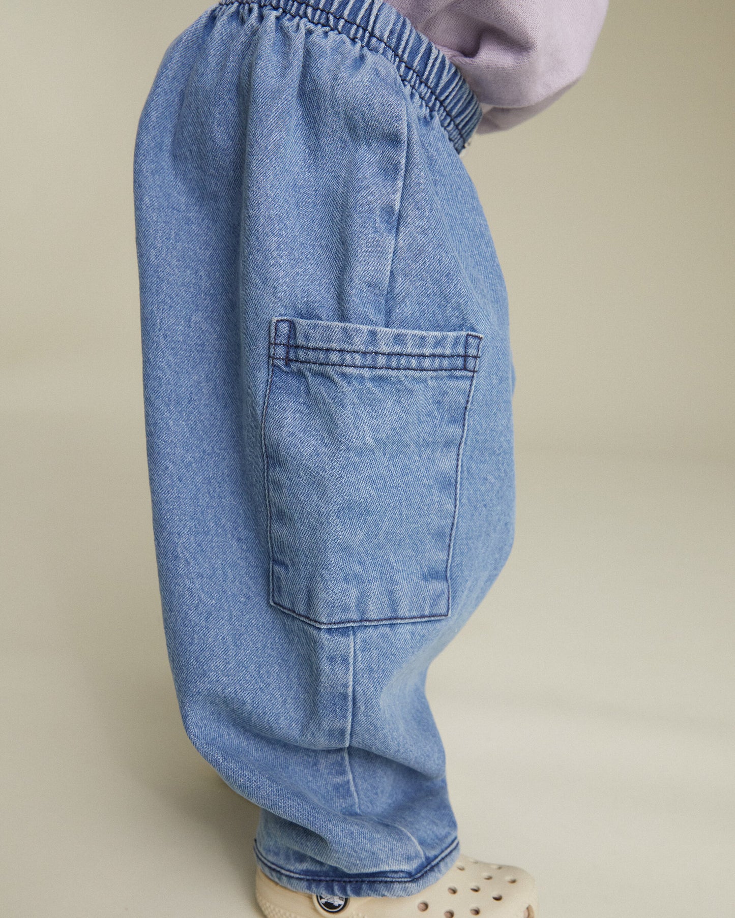 Light blue jeans worn by a person on a beige background