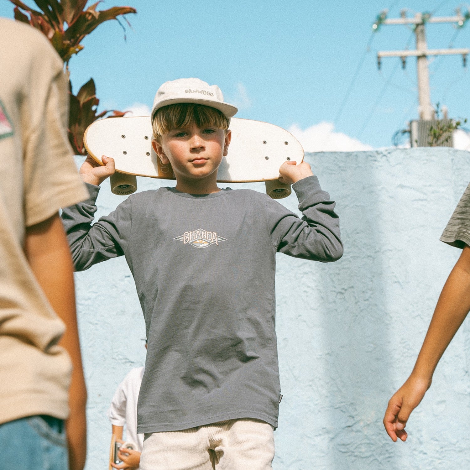 Child holding a skateboard with a clear sky background