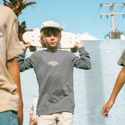 Child holding a skateboard with a clear sky background