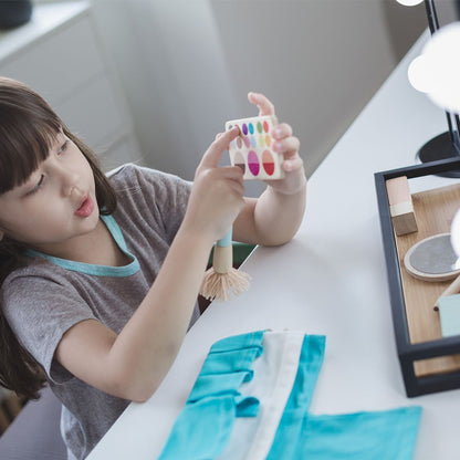 Child holding a small colorful object on a white surface