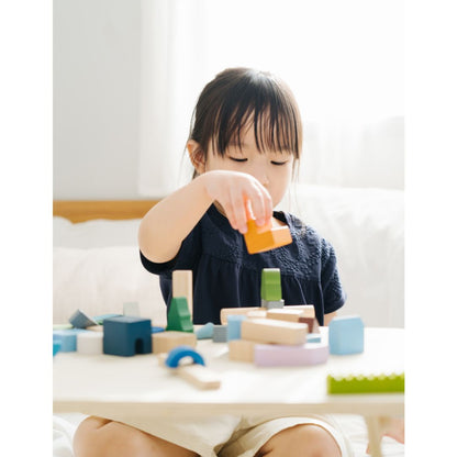 Child playing with colorful building blocks on a table.