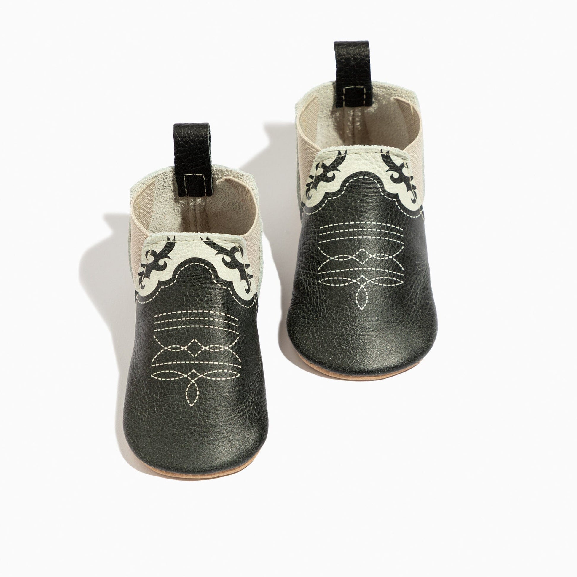 Pair of black leather baby boots with white stitching on a white background