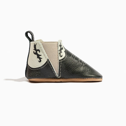 Black baby bootie with decorative elements on a white background