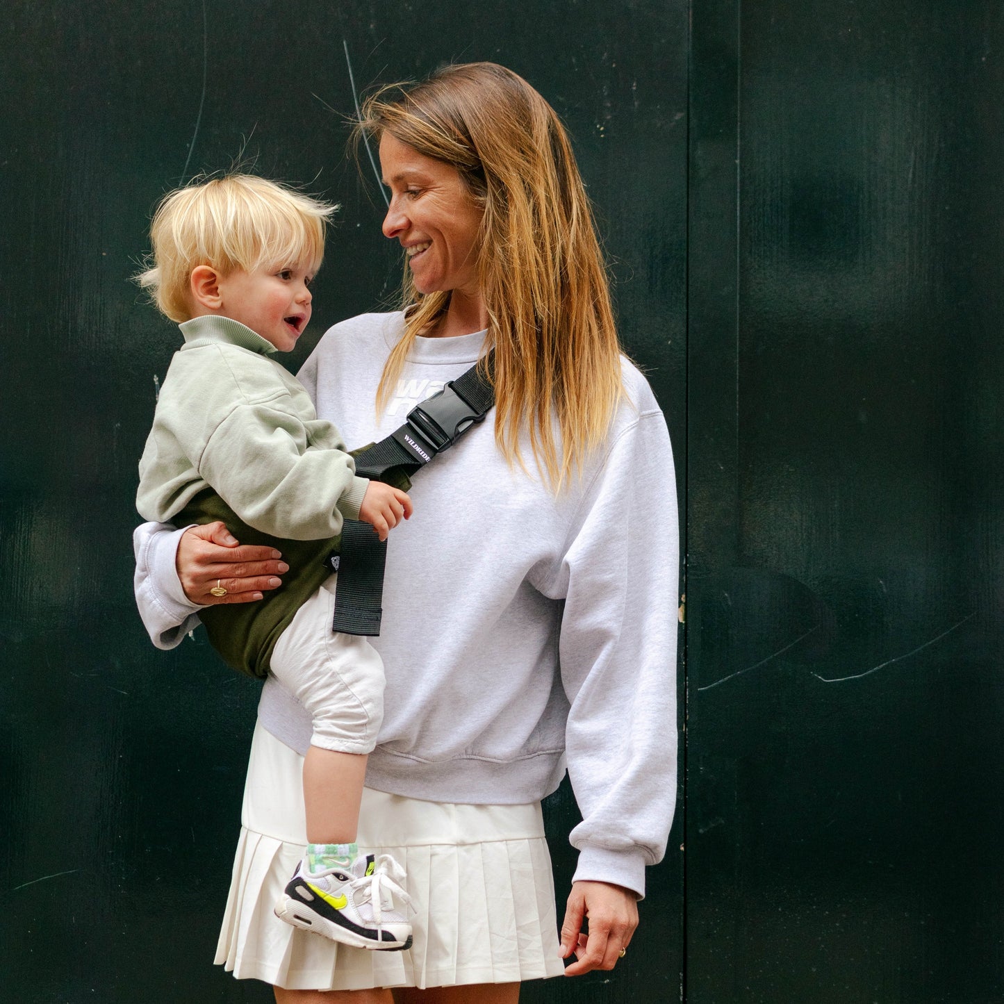 Woman holding a child in a carrier against a dark background
