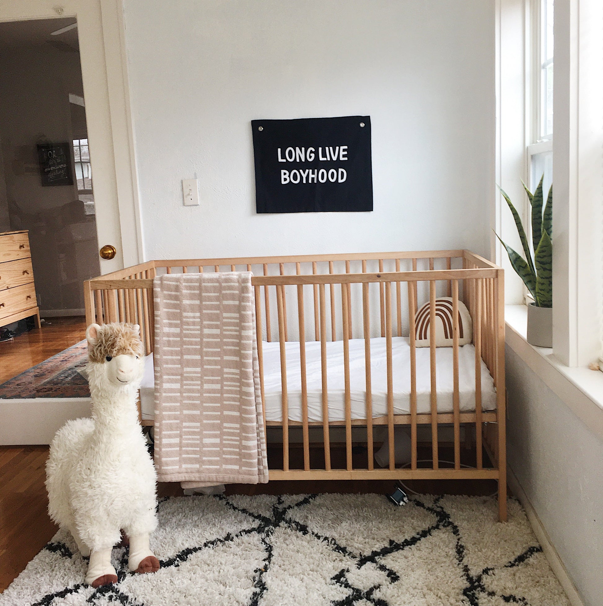 Nursery room with wooden crib, plush toy, and wall hanging.